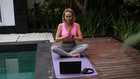 Mid adult woman practicing exercise while using laptop at poolside. High quality 4k footage