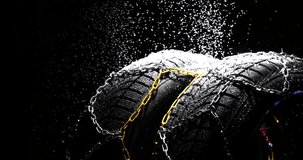 Winter Car tire with snow chains on black background. Winter season, 4k video snowing