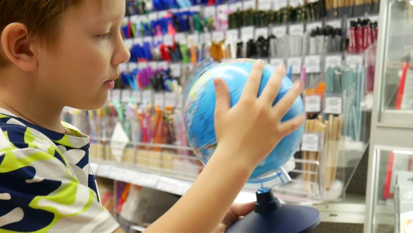 A boy spinning a globe in his hands close-up