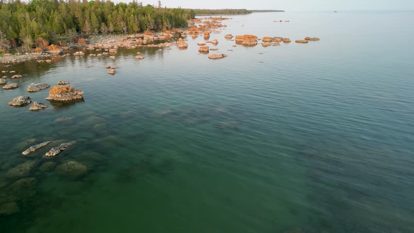 Aerial pan over water to coastline with boulders, Lake Huron, Michigan
