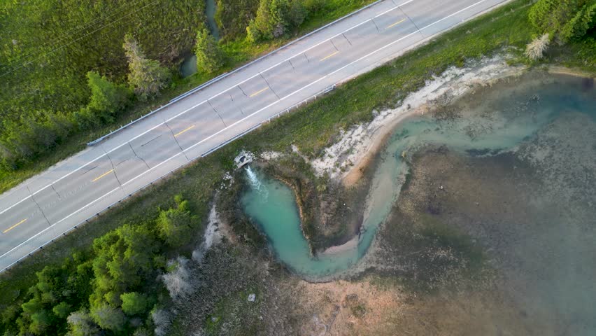 Aerial topdown ascent of Quarry lake stream water emptying into Lake Huron, Michigan