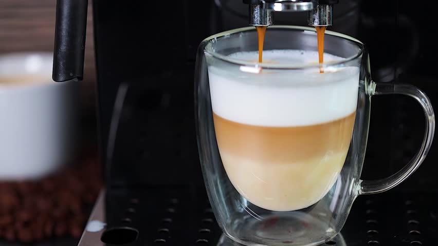 Close-up of coffee being poured into a glass cup with milk, making cappuccino with an automatic coffee machine. Coffee. Royalty-Free Stock Footage #1109080315