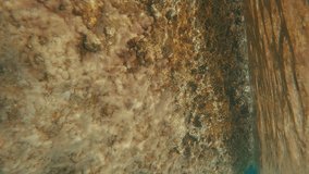 Vertical video, POV underwater shot, man swims to rocky shore and climbs up coastal stones, Split level, First person video, Close up, Mediterranean sea, Greece