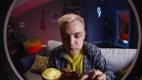 Male blogger streamer eats chicken on camera for video on social networks, streaming on online platforms. Chef appetizingly tasty eats chicken legs, smeared in sauce. Review of delicious homemade food