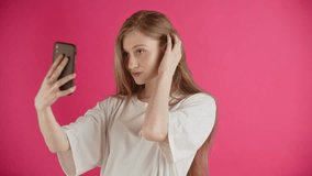 A young woman blogger with a mobile phone takes a selfie and shoots a video of herself to send to a casting for a movie, advertisement or a modeling school. Happy ginger girl in positive emotions of