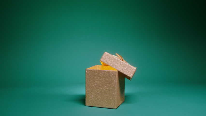 Christmas scene on green background, copy space slow motion RED camera. Merry Christmas, 2024 year. Magical night background with elegant glittery golden gift box with open cover and light seen inside