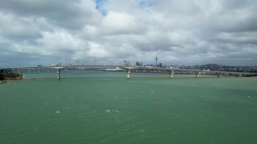 Auckland Harbour Bridge Overlooking Turquoise Waitemata Harbour and Downtown Skyline from an Aerial Drone Panning Across the Waters in New Zealand.