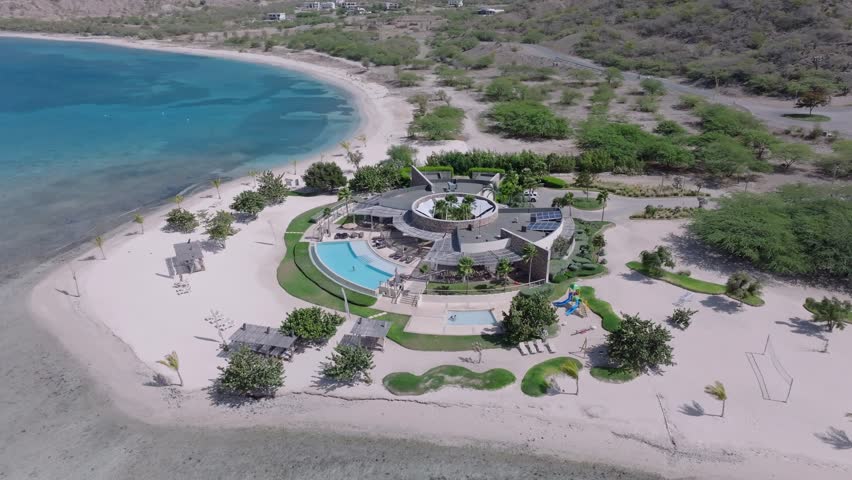 Waterfront luxury resort structure with swimming pool at Puntarena, Bani in Dominican Republic. Aerial drone orbiting