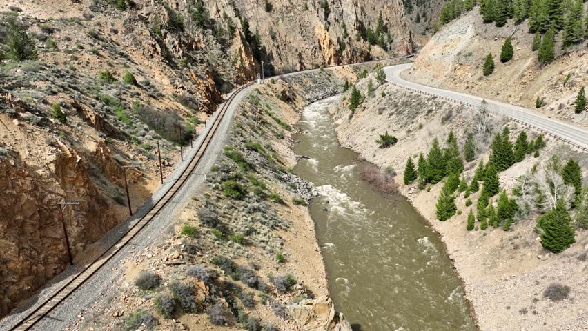Aerial shot of the train tracks and road along the Colorado River as it runs through a narrow canyon in Colorado