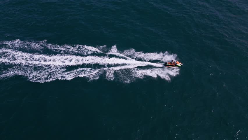 Aerial view of a personal watercraft speeding through the waves, creating a mesmerizing trail. Royalty-Free Stock Footage #1109098191
