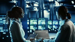 Coworkers programming in server hub housing advanced infrastructure storing massive datasets. Employees running code on laptop to update data center racks doing complex computational operations - Powered by Shutterstock - Get 15% off with code: PIKWIZARD15