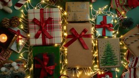 Top view on green background decorated with gift boxes, Christmas decorations and glowing garlands. Golden Christmas lights illuminates present tied with red satin ribbons, rotating shot on RED camera - Powered by Shutterstock - Get 15% off with code: PIKWIZARD15