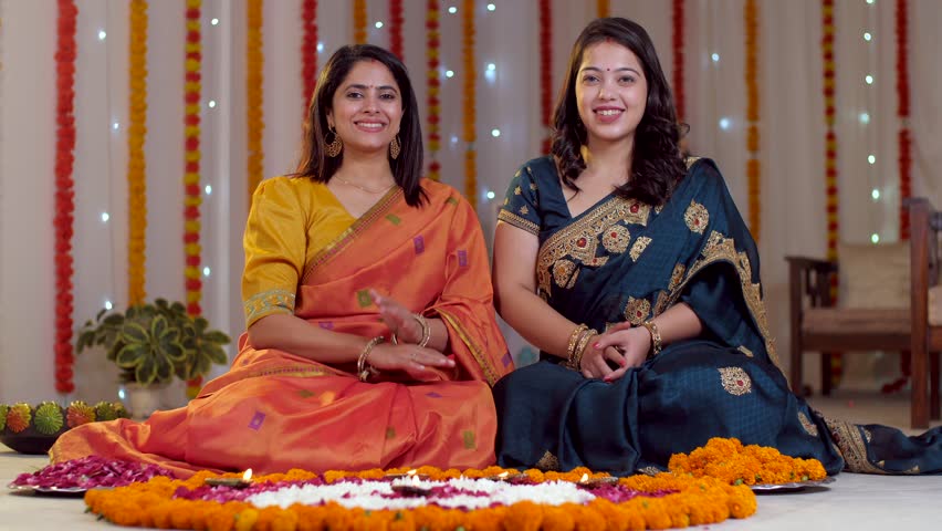 Two females in colorful ethnic Indian sari and bindi welcoming guest for festival in namaste pose - Indian tradition, Diwali celebration. Attractive women celebrating Diwali festival at home - fest...