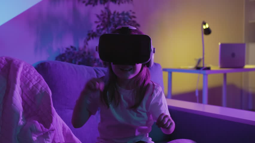 Little Girl Uses Virtual or Augmented Reality Glasses Sitting On A Bed in Dark Room, VR Headset User On Digital Interactive Art Performance, Entertainment Of Future Royalty-Free Stock Footage #1109108927