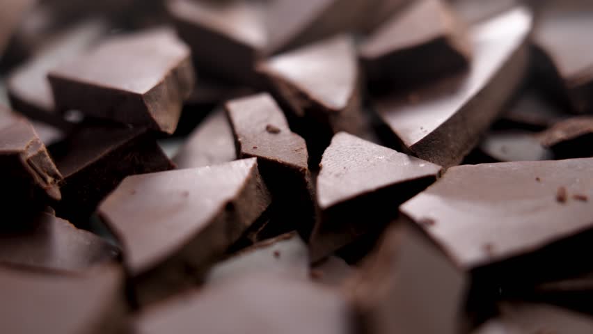 Broken crushed dark chocolate bits close up. Delicious sweet cocoa ingredient. Rotation Royalty-Free Stock Footage #1109109259