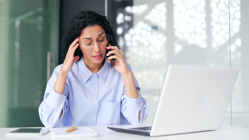 Angry female employee or manager arguing talking on mobile phone while sitting at desk at workplace in modern office. Frustrated brunette businesswoman argues with subordinates explaining the problem | Shutterstock HD Video #1109109413