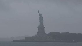 4K video with Liberty Statue in Manhattan covered by clouds during a storm rainy day in New York, view from the ferry. Travel to America.
