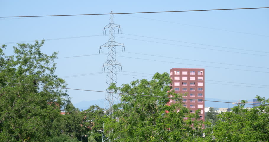 Elevated view of a contemporary apartment building in Strasbourg, framed by green trees and an electricity pillar in the foreground.