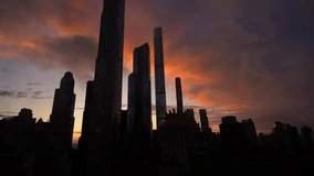 Time lapse 4k video in Manhattan with silhouettes of skyscraper office buildings against amazing orange color sunset sky, after a rain. Travel to New York, America.