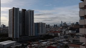 High-angle 4K video that sees condominiums of various sizes encircling the city center, business district, and blurry lights and passing cars during the evening twilight sky.