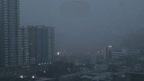 High-angle 4K video that sees condominiums of various sizes encircling the city center, business district, and blurry lights and passing cars during the evening twilight sky.