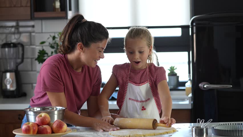 Video of beautiful happy mother and daughter preparing an apple pie at home kitchen. Autumn fun family activities Royalty-Free Stock Footage #1109119137