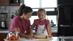 Video of beautiful happy mother and daughter preparing an apple pie at home kitchen. Autumn fun family activities