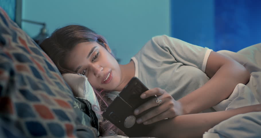 Indian upset sad alone woman crying lying on bed using mobile phone chatting late night at indoor home. Lonely unhappy female looking on smartphone screen typing reading bad massage at inside house | Shutterstock HD Video #1109119319