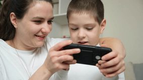 Mom and son playing a video game together on a smartphone. Fun pastime, common interests of the child and parents