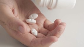 Woman taking three white pills into hand, macro. Three big white pills oval elongated shapes fall into palm of hand from pill bottle.  - Powered by Shutterstock - Get 15% off with code: PIKWIZARD15