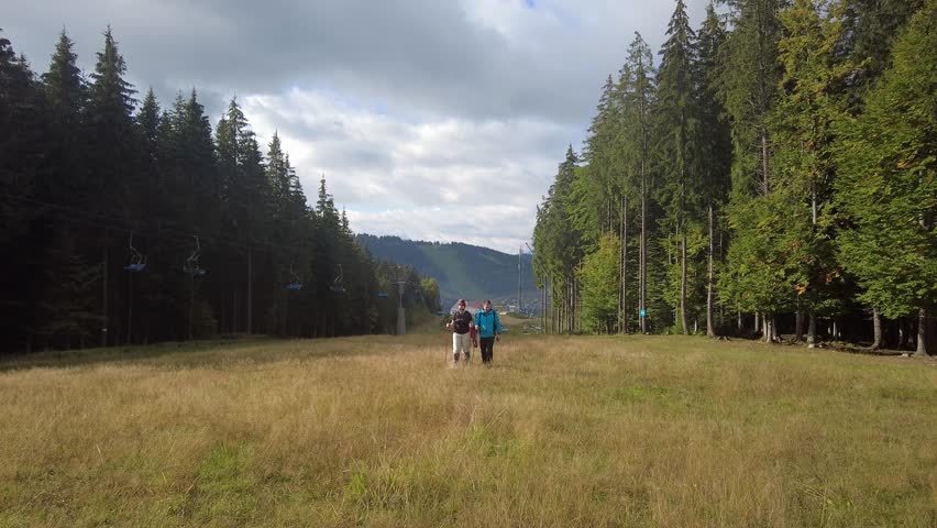 On a sunny day, a man and a woman go hiking.