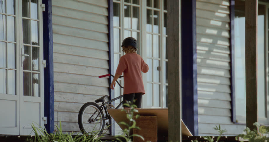 Caucasian kid boy preparing to do a crazy bicycle trick jump on a homemade trampoline near his house