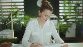 Eco real estate business. Closeup on elegant woman realtor in modern green office in white blouse with calculator and document. - Powered by Shutterstock - Get 15% off with code: PIKWIZARD15