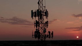 Television or radio telephone tower in a cityscape at sunset time. Aerial zoom shot footage