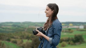Video of pretty woman photographer taking pictures in the beautiful mountain landscape