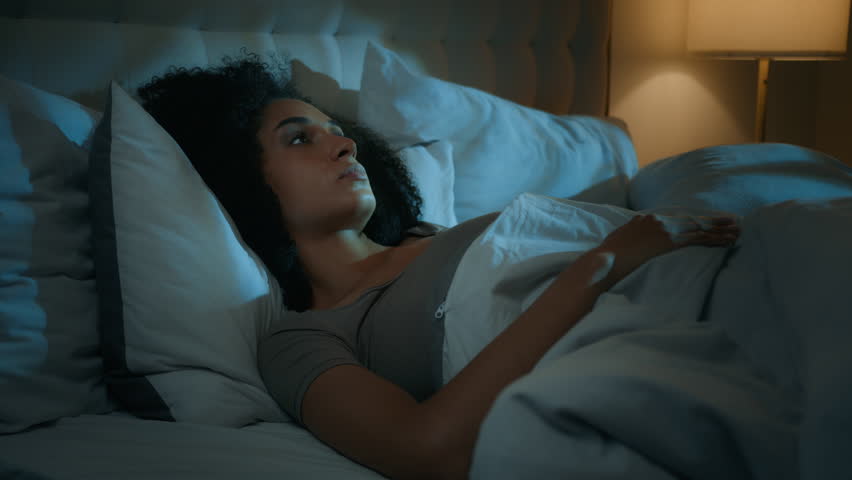 Noisy neighbours problem annoyed African American woman lying in bed night dark bedroom suffer from sleeping disorder insomnia sleepless angry girl trying sleep awake to noise cover ears with pillows Royalty-Free Stock Footage #1109140601