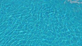 View of clean clear water in swimming pool. Ripples and waves of water with reflection on bottom. Calm relaxing video. Pool water surface.