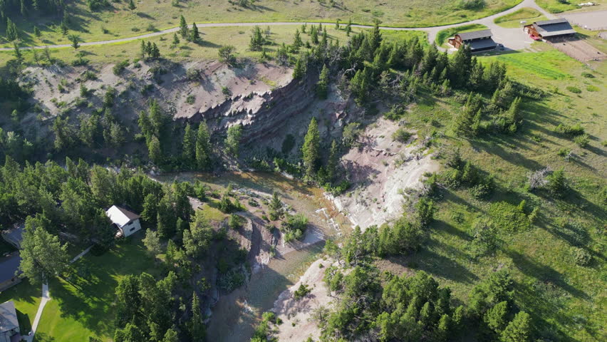 Rocky Cliff Covered in Evergreen Trees Next to River During Sunset