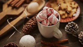 Pastel Christmas decoration on the table with flickering bulbs and hot drink with marshmallow - Powered by Shutterstock - Get 15% off with code: PIKWIZARD15