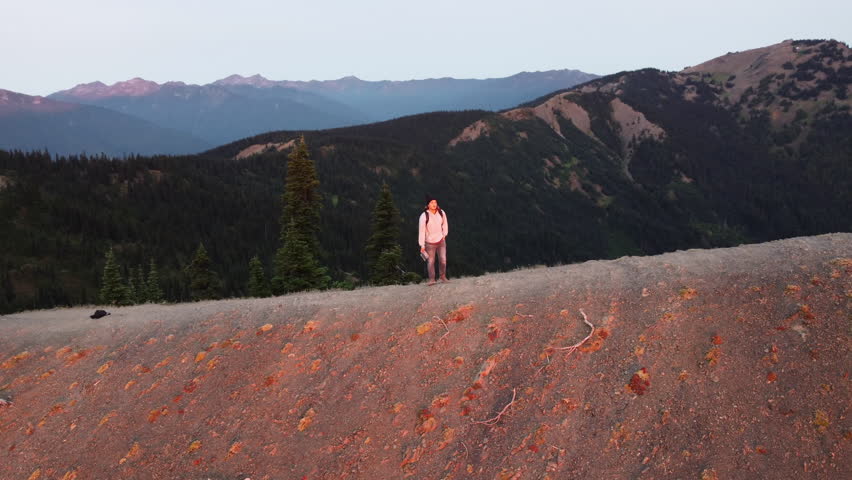 Man Walking on Mountaintop Overlooking Valley at Sunrise, Drone Arc POV, Olympic National Park, Washington
