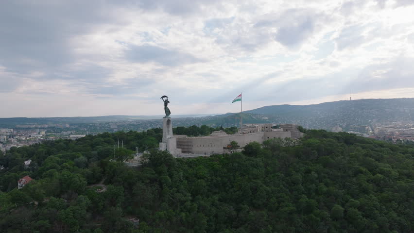 Forwards fly above trees in park. Historic Citadella fortification on top of Gellert Hill. Budapest, Hungary
