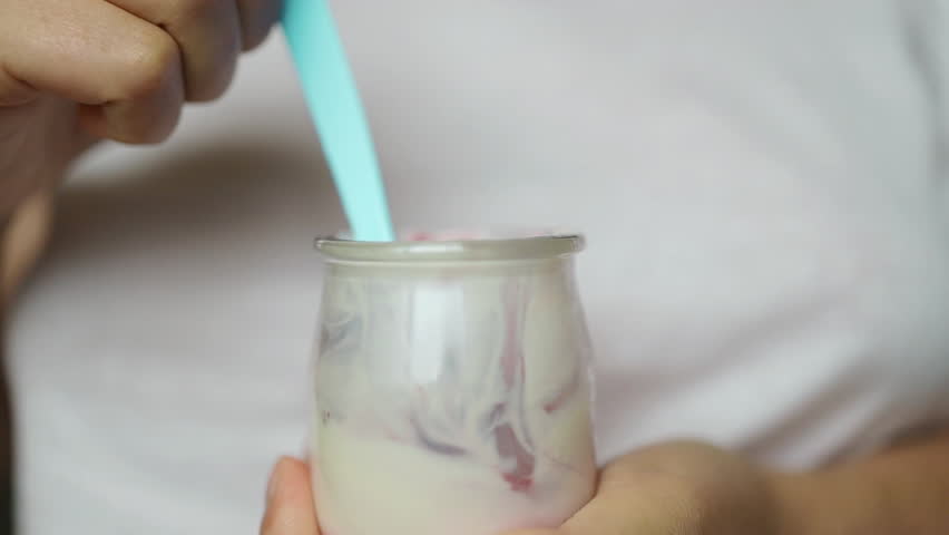 Caucasian woman having healthy breakfast at home with fruit and yogurt. Happy natural girl holding teaspoon with yogurt and blueberries, closeup. High quality FullHD footage