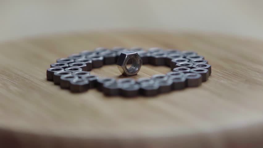 A bunch of bolts lies on a rotating wooden table | Shutterstock HD Video #1109154337