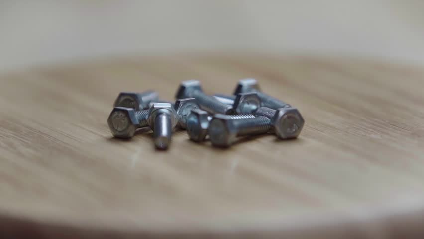 A bunch of bolts lies on a rotating wooden table | Shutterstock HD Video #1109154343