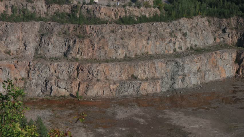 Beautiful granite quarry during the day. Lots of stones. Stones overgrown with trees and grass. Trees sway in the wind. Top view of the stone quarry.