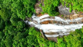 Breathtaking tropical forest waterfall, framed by vibrant greenery, captured from a mesmerizing aerial perspective with a drone. Nature and forest concept. Chiang Mai, Thailand.
