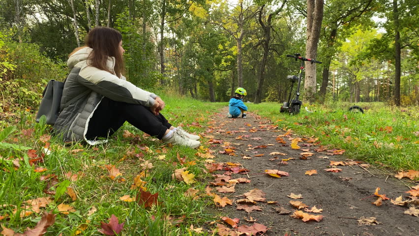 mother with child little boy on electric scooter in autumn park