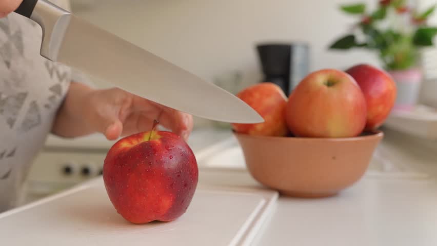 Woman uses sharp kitchen knife to cut ripe large red apples into slices. Preparing apples for drying. slow motion | Shutterstock HD Video #1109165757