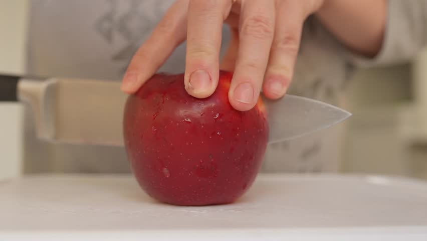 Woman uses sharp kitchen knife to cut ripe large red apples into slices. Preparing apples for drying. slow motion | Shutterstock HD Video #1109165761