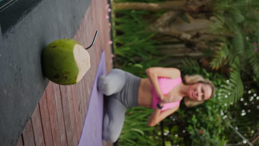 Mid adult woman sitting at namaste position, green fresh coconut is ready for drinking, outdoors exercises | Shutterstock HD Video #1109166881